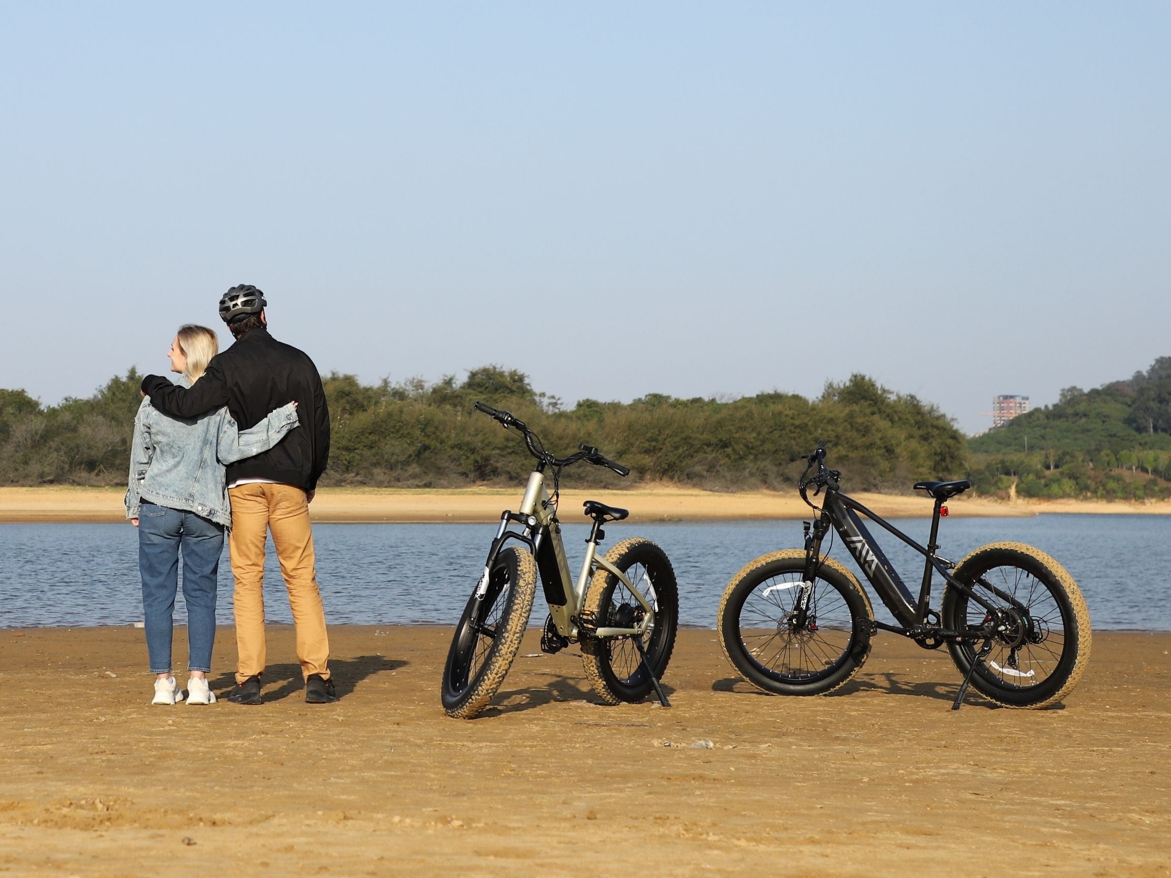 Couple riding TST Ebike electric bike outdoors on lake.